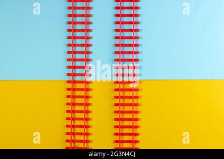 Spielzeugeisenbahnschienen auf farbigem Hintergrund. Draufsicht Stockfoto