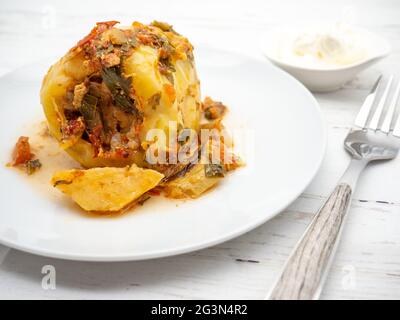 Nahaufnahme einer köstlichen Mahlzeit mit Paprika, gefüllt mit Hackfleisch neben saurer Creme auf einem Tisch Stockfoto
