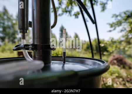 Alkoholmashine in einem Dorfhof, auf einem verschwommenen Hintergrund. Zubereitung eines berauschenden Getränks. Nahaufnahme. Stockfoto