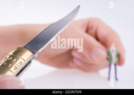 Hand, die ein Taschenmesser in der Nähe einer Figur hält Stockfoto