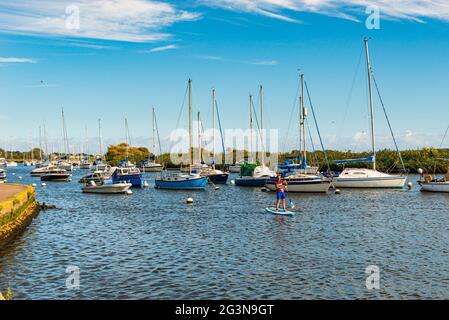 Mann auf einem Paddelbrett inmitten kleiner Boote im Hafen von Christchurch, Dorset Stockfoto