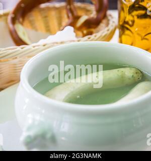 Stillleben mit weißen münchner Würsten in Topf, Bier und Brezel. Flacher Freiheitsgrad! Stockfoto