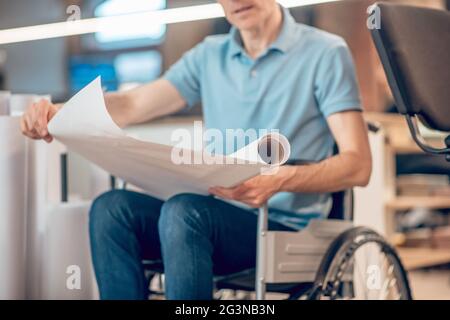 Papierrolle in den Händen eines Mannes im Rollstuhl Stockfoto