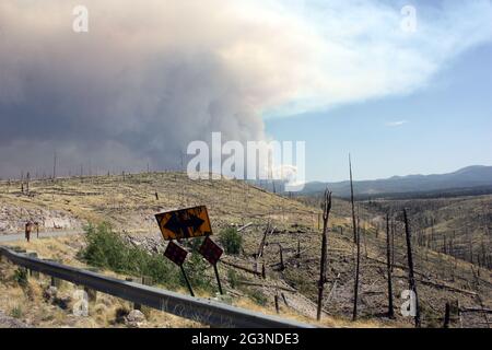 Wabender Rauch vom aktuellen Gila National Forest Johnson Feuer hinter gebogenem Straßenschild in altem Brand Stockfoto