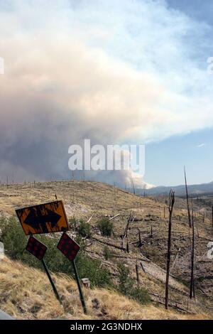 Wabender Rauch vom aktuellen Gila National Forest Johnson Feuer hinter gebogenem Straßenschild in altem Brand Stockfoto