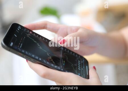 Weibliche Hand mit Smartphone Aktien online im Coffee Shop Business Concept handeln Stockfoto