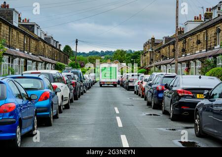 Asda Lieferwagen parkte auf der Straße (Route blockiert) zwischen den Reihen geparkter Fahrzeuge außerhalb von Steinterrassenhäusern - Burley in Wharfedale, Yorkshire, Großbritannien. Stockfoto