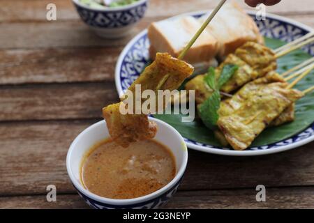 Lokale Thai-Küche Schweinefleisch Satay mit oeanut Dipping Sauce isoliert Im Holzhintergrund Stockfoto