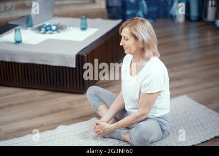 Eine Frau im Alter von über 50 Jahren ist Yoga zu Hause. Stockfoto