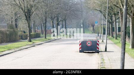 Große Pflanzmaschine, die als Straßensperre dient und die Geschwindigkeitsbegrenzung von 30 km/h durchsetzt Stockfoto