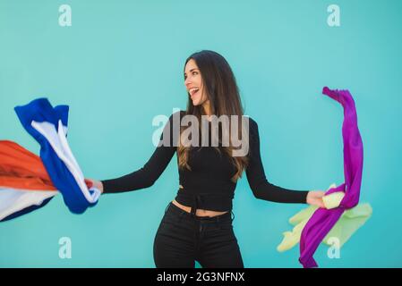 Happy Shopper mit verschiedenen fliegenden Textilien auf aquamarinfarbenem Hintergrund Stockfoto