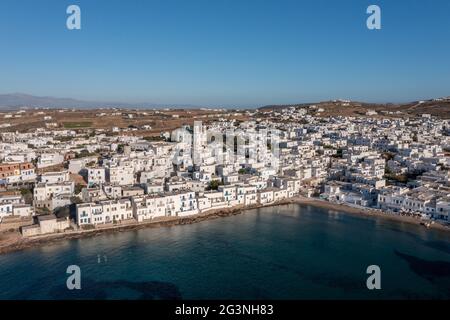 Insel Paros, Griechenland, Kykladen. Naousa Stadtbild Luftdrohne Ansicht. Weiße Gebäude am Wasser mit blauen Fenstern, kykladische Architektur. Ruhige Lage Stockfoto