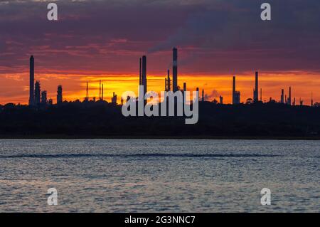 Ein Blick auf die Silhouette der Fawley-Ölraffinerie auf Southampton Water bei Sonnenuntergang - Juni 2005. Stockfoto