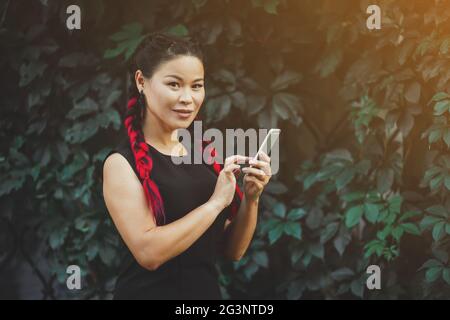 Wunderschöne reife asiatische weibliche Modell mit Smartphone Outdoor Stockfoto