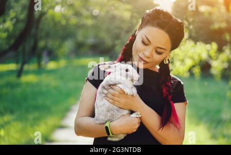 Hübsche Asiatin Hugging Bunny auf Sommer Natur Stockfoto