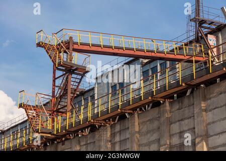 Eine alte, rostige Maschine, die mit Metalltreppen und Deckenförderern ausgestattet ist, in der Betonmischanlage. Notausflucht aus dem Industriegebäude. Stockfoto