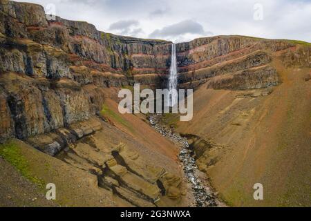 Luftaufnahme des Hengifoss Wasserfalls in Ostisland. Hengifoss ist der dritthöchste Wasserfall Islands und wird von basaltischen Schichten mit roten umgeben Stockfoto