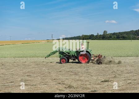 Landwirt Traktor schaltet das Gras für eine bessere Trocknung Stockfoto