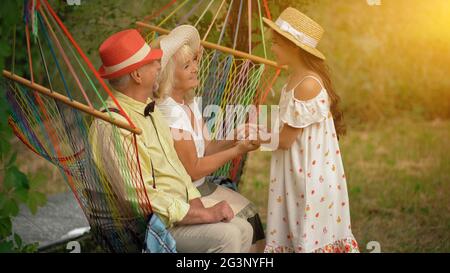 Das alte Ehepaar sitzt in der Hängematte im Garten Stockfoto