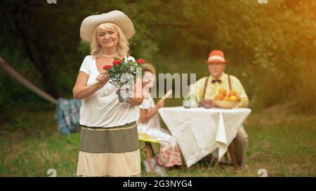 Eine Frau steht im Garten ein Blumentopf in der einen Hand und ein Gärtner Kelle in der anderen Hand Stockfoto