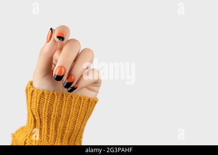 Gepflegte Womans Hand auf weißem Hintergrund. Trendy Herbst halloween orange Nagel-Design Stockfoto