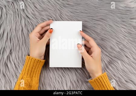 Gepflegte Damen Hand halten Postkarte auf grau flauschigen Hintergrund Stockfoto