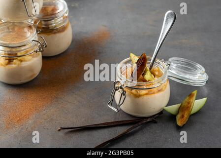 Apfel- und Zimtpudding in einem Glasgefäß auf dunklem Steingrund Stockfoto