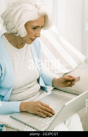 Grauhaarige Frau verwenden Laptop für Online-Shopping oder Banking Stockfoto
