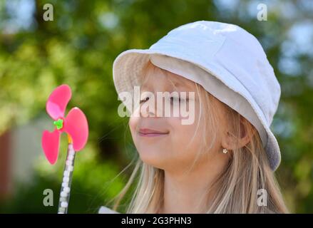 Kleines Mädchen, das im Sommer auf einen Fan bläst. Stockfoto