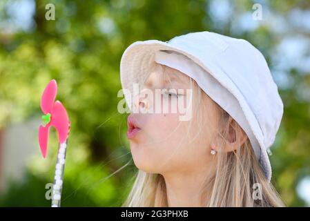 Kleines Mädchen, das im Sommer auf einen Fan bläst. Stockfoto