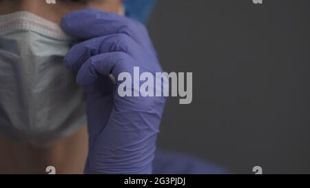 Ärztin in Handschuhen zur Befestigung der Schutzmaske, Nahaufnahme Stockfoto