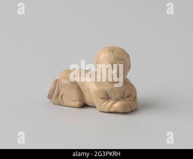 Eine krabbelnde Kinderfigur aus Speckstein. Eine kriechende Kinderfigur aus elfenbeinfarbenem Speckstein. Auf der Rückseite von schikanieren Blumenzweigen. Stockfoto