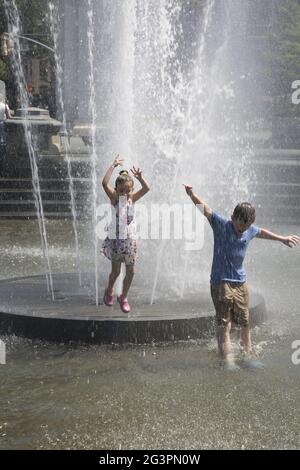 An einem 90-Grad-Junitag in New York City kühlen sich die Kinder im Washington Square Brunnen ab. Stockfoto