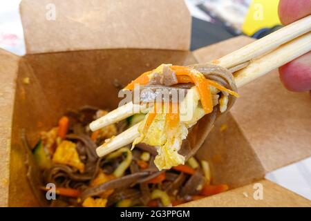 Selektive Fokusaufnahme eines Mannes, der mit Essstäbchen frische Gemüse-Soba-Nudeln isst Stockfoto