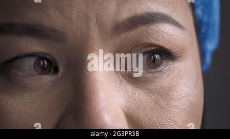 Überarbeiteter Medic fühlt sich nach einer langen Überstunden Stress. Super Nahaufnahme von müden Augen des Arztes. Frau mit schützendem Hutlook Stockfoto