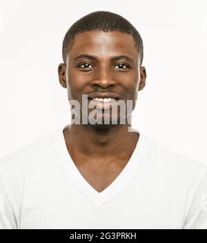 Positiver Afro-amerikanischer Mann, der die Kamera anschaut. Porträt eines dunkelhäutigen, fröhlichen Mannes in weißem T-Shirt, isoliert auf weißer BA Stockfoto