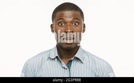 Überrascht afro-amerikanischen Geschäftsmann. Junger staunender Mann blickt mit geöffnetem Mund und staunenden Augen auf die Kamera. Schneiden Sie das Hochformat ein Stockfoto