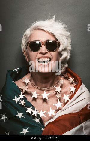 Lachende ältere Frau in Sonnenbrille mit amerikanischer Flagge Stockfoto