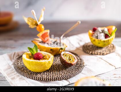 Helle Food-Fotografie einer Mischung aus geschnittenen tropischen Früchten. Hintergrund mit einem Tablett mit Passionsfrucht, Maracuya, Physalis, Orange, Drachenfrucht und Himbeer Stockfoto