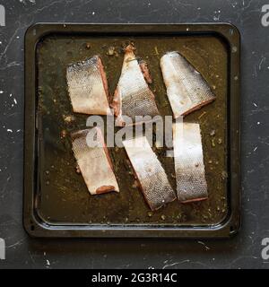 Lachsstücke mit Haut in Speiseöl und einige Kräuter auf der Bratpfanne - zum Backen Stockfoto