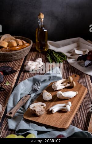 Dunkle Fotografie von Pilzen, Spargel, Brot, Knoblauch und Pflaumen auf einem Tisch aus altem Holz. Gemüse Rezept für Herbst oder Winter. Moody Bild von Stockfoto