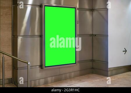 Werbetafel zeigt grünes Modell auf Stahlwandfliesen an unterirdischer Passage Stockfoto