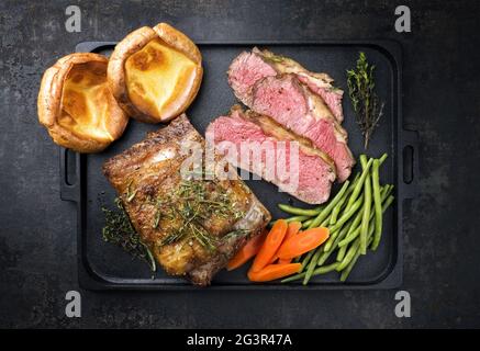 Traditionelle Commonwealth Sonntag Braten mit Aufschnitt Aufschnitt Roastbeef Mit Gemüse und Yorkshire Pudding als Draufsicht auf einem Mod Stockfoto