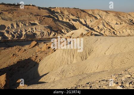 Nachal Zin gegenüber von Sde Boker und Risslinien im Sandsteingelände bei Sonnenuntergang ist es ein trockenes Flussbett in der Negev-Wüste, Israel. Stockfoto