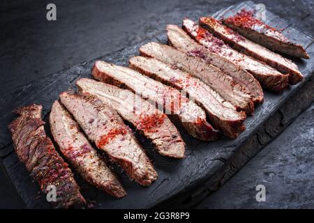 Traditionelles Barbecue-Steak mit trockener, gereiftem Wagyu-Flanke und Chilipulver als Nahaufnahme bei einem rustikal verkohlten Holzschnitt Stockfoto