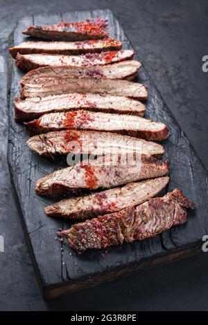 Traditionelles Barbecue-Steak mit trockener, gereiftem Wagyu-Flanke und Chilipulver als Nahaufnahme bei einem rustikal verkohlten Holzschnitt Stockfoto