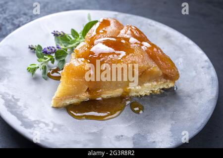 Traditionelles französisches Tatin mit Äpfeln und Vanille als Nahaufnahme auf einem modernen Design-Teller mit rustikalem Hintergrund Stockfoto