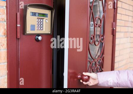 Kaukasische weibliche Hand öffnen Stahl schwere Tür nach Intercom-Kommunikation Stockfoto