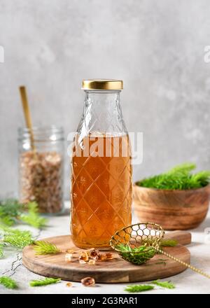 Flasche hausgemachten Sirup aus jungen Fichtenspitzen und Naturzucker auf dem Holzschneidebrett. Stockfoto
