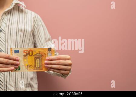 Finanzielle Unterstützung für das Kind. 50 Euro in den Händen eines Kindes als Konzept der materiellen Unterstützung für Kinder, Unterhaltszahlungen, Investitionen. Stockfoto